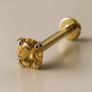 14K yellow gold citrine flat back labret with 4-prong setting, angled studio shot on beige background