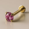 14K yellow gold flat back labret with 2mm pink sapphire in four-prong setting, angled studio view