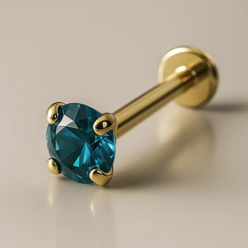 14K yellow gold flat back labret with 2mm blue zircon in four-prong setting, angled studio view