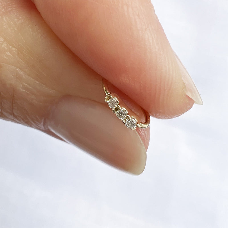 14k yellow gold three-diamond seam ring hoop held between fingers for size reference