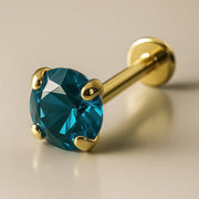 14K yellow gold flat back labret with 3mm blue zircon in prong setting, angled studio view