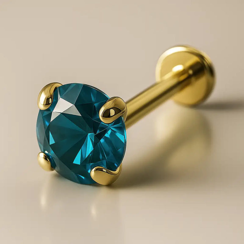 14K yellow gold flat back labret with 3mm blue zircon in prong setting, angled studio view