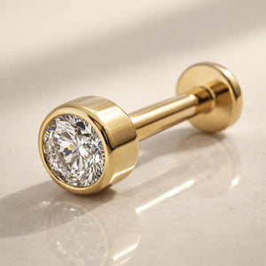 14k yellow gold 3mm diamond bezel-set flat back labret stud on marble surface, angled hero shot