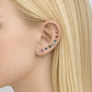 Rainbow of 3mm prong-set gemstone threadless stud ends worn across multiple ear piercings on model