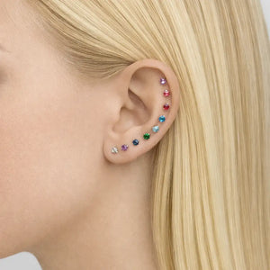 Rainbow of 3mm prong-set gemstone threadless stud ends worn across multiple ear piercings on model