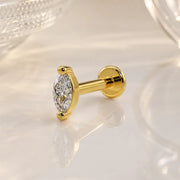 14k yellow gold 3mm marquise diamond flat back labret stud on marble surface, angled lifestyle shot