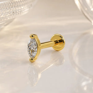 14k yellow gold 3mm marquise diamond flat back labret stud on marble surface, angled lifestyle shot