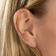 Pear-cut diamond flat back stud worn in lobe piercing, styled with gold ear crawler for scale