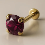 14K yellow gold prong-set labret with 3mm rhodolite garnet, angled hero view showing flat disc back