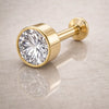 14k yellow gold 4mm CZ bezel-set flat back labret resting on linen surface, side angle view