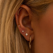 14k gold diamond bezel flat back stud styled in a curated ear with multiple gold cartilage piercings