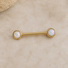 Gold nipple ring barbell with opal stones on a beige background in solid 14k yellow gold
