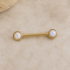 Gold nipple ring barbell with opal stones on a beige background in solid 14k yellow gold