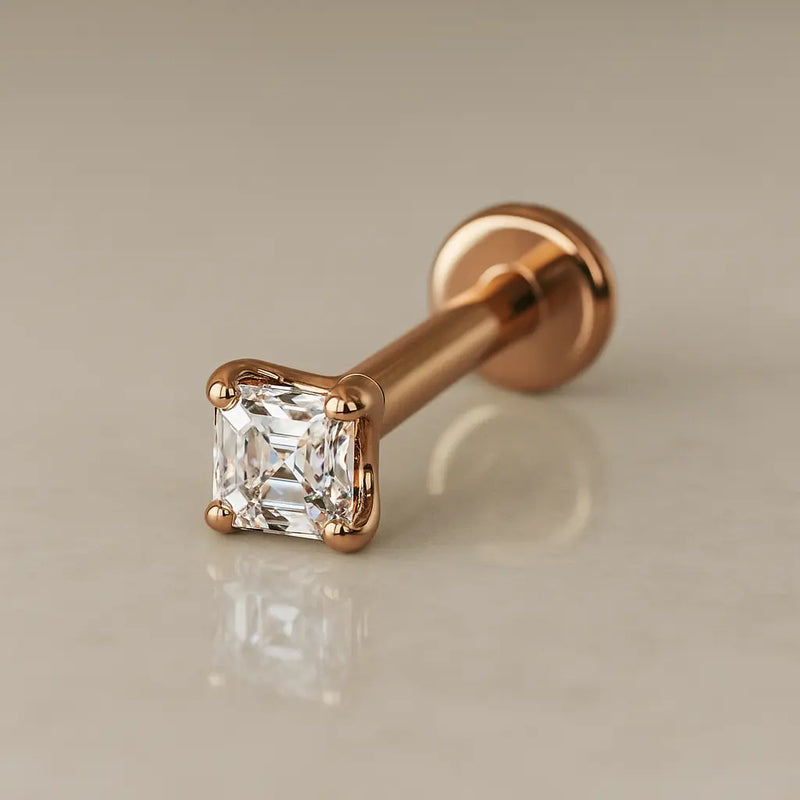 14k rose gold 2mm Asscher-cut diamond flat back labret stud, angled lifestyle shot on neutral surface