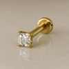 14k yellow gold 2mm Asscher-cut diamond flat back labret stud, angled lifestyle shot on neutral surface
