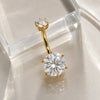 Astra II belly ring in yellow gold with moissanite gemstone on a glass surface.