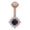 14k rose gold belly ring with blue sapphire center stone set in diamond halo flower design, front view