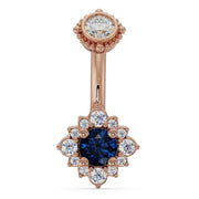 14k rose gold belly ring with blue sapphire center stone set in diamond halo flower design, front view