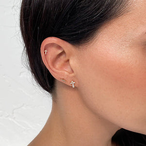 Gold lightning bolt stud shown styled in a curated ear with multiple cartilage piercings on model