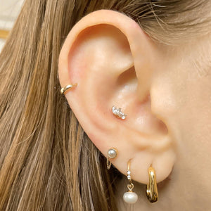 Pearl charm add-on worn on gold hoop lobe piercing, shown styled with multiple ear piercings