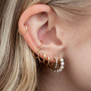 Gold seam rings styled in multiple ear piercings including helix and lobe, curated ear look