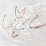 Assorted 14K gold piercing chain connectors in yellow, white, and rose gold styles on marble surface