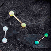 Opal straight barbells in white and teal with rose gold and silver shafts arranged on dark slate rock