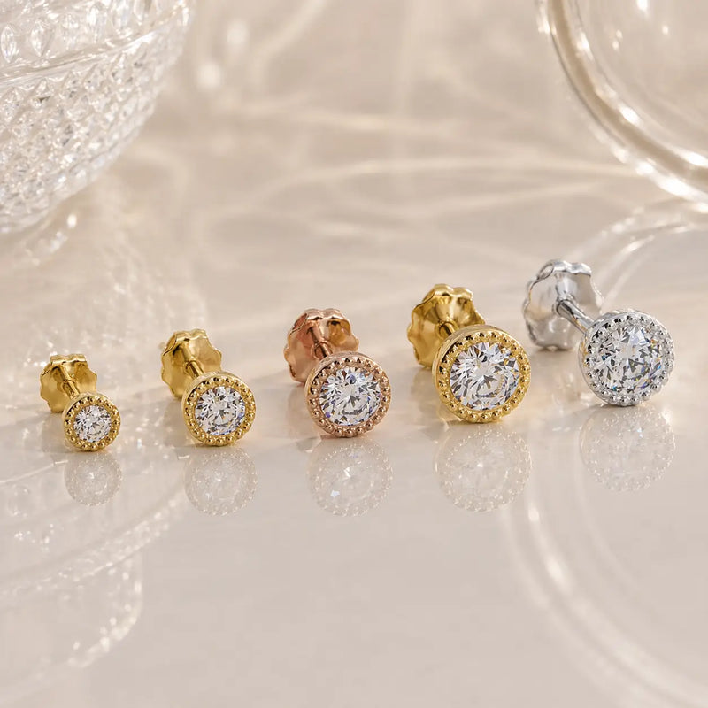 Set of diamond stud earrings in gold and silver on a light background
