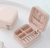Pink travel jewelry box open showing ring rolls and earring pockets storing gold and crystal rings