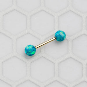 Teal opal 14k yellow gold straight barbell laid on hexagonal tile surface, showing vibrant color fire