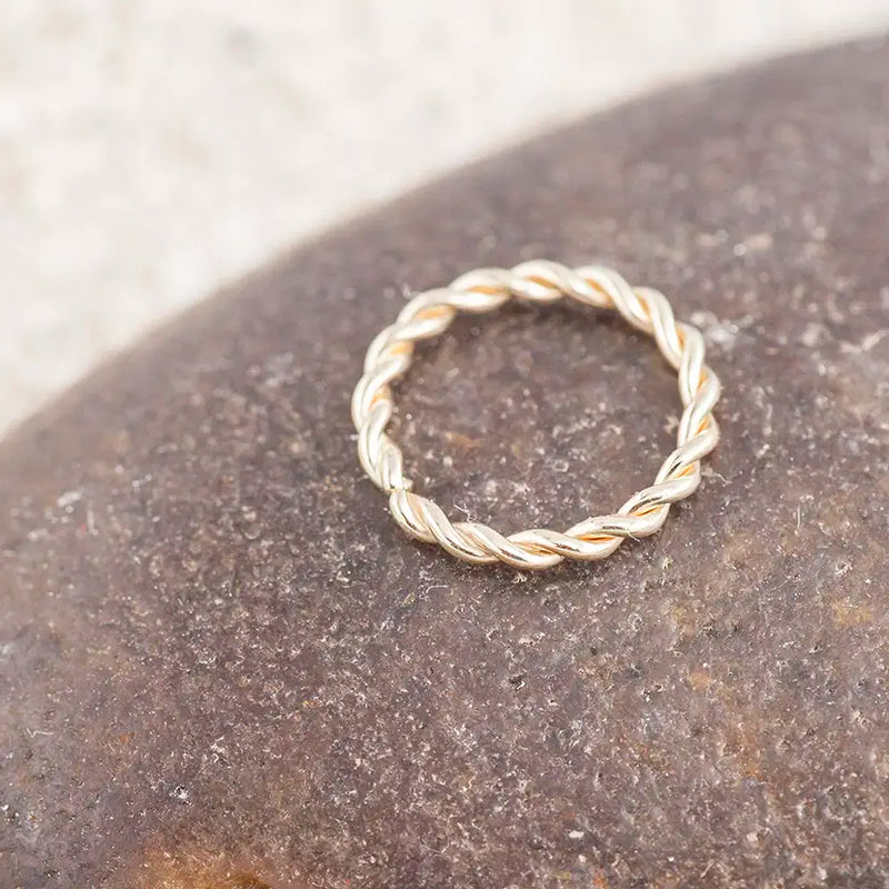 14K white gold twisted seam ring resting on dark stone surface, showing rope-twist detail
