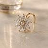 Gold nose ring with diamond flower charm on a reflective surface