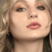 14K gold segment ring worn as a septum piercing on a female model, front face view