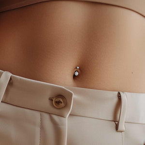 14k gold La Reina diamond halo belly ring shown in navel piercing with neutral outfit