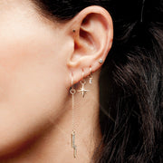 Gold north star charm on a hoop earring in a layered ear stack, side profile showing dangle fit