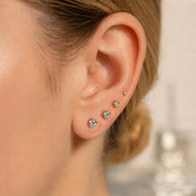 14K gold bezel-set diamond studs in multiple sizes styled as an ear stack on a model