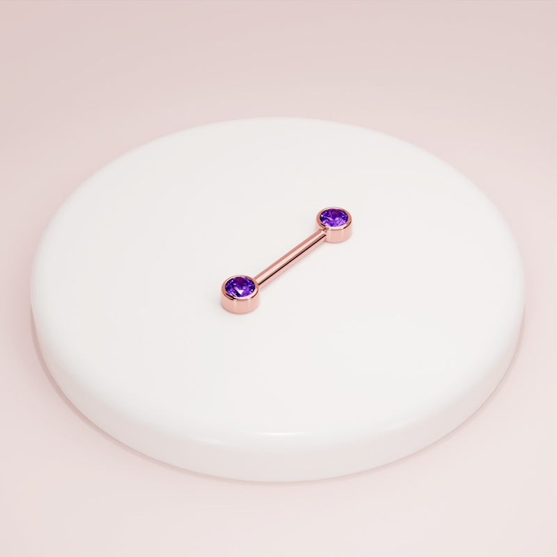 14K rose gold amethyst nipple barbell resting on white ceramic dish, styled product shot