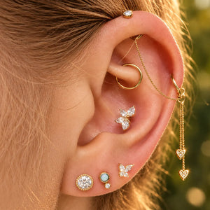 Curated gold ear stack featuring a diamond butterfly stud, perlage and French milgrain studs with connecting chains
