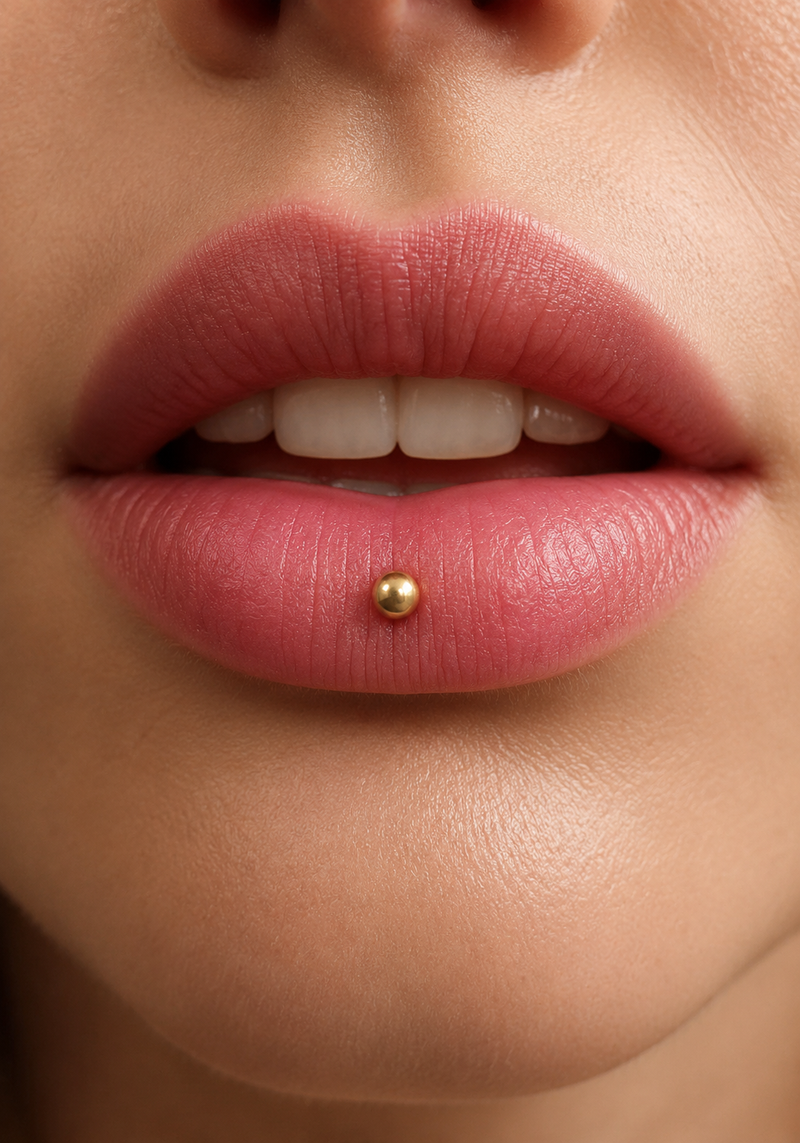 Ashley piercing with a gold ball stud set in the centre of the lower lip
