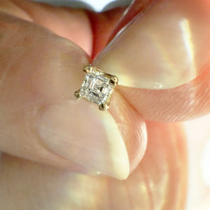 2.3mm Asscher-cut diamond labret end held between fingers to show actual tiny size reference