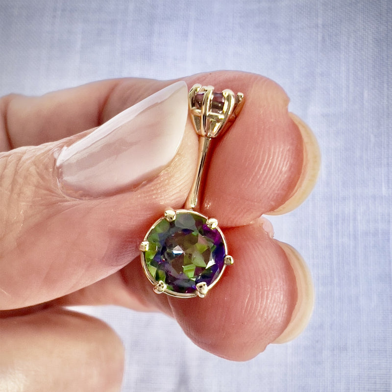 14k yellow gold belly ring with mystic topaz held in hand showing multicolor gem and size scale