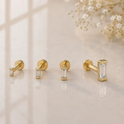 All four sizes of 14k yellow gold baguette diamond flat back studs displayed on marble surface