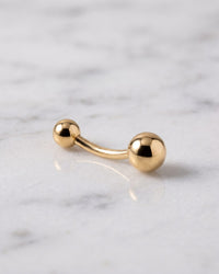Classic belly rings - 14k yellow gold curved navel barbell with double gold balls on white marble