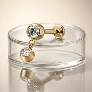 14k yellow gold bezel diamond dangle flat back stud resting on clear glass dish, lifestyle shot
