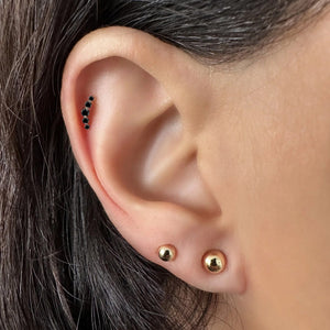 Black diamond mini climber stud shown in a helix cartilage piercing on model's ear