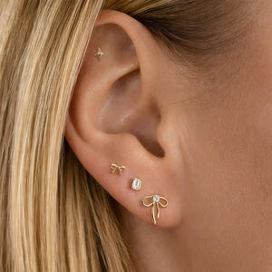 14k gold ribbon bow diamond flat back stud worn in lobe piercing, styled in curated ear stack