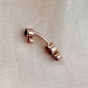 Side profile of 14k rose gold garnet bubble bezel belly ring showing curved barbell shape