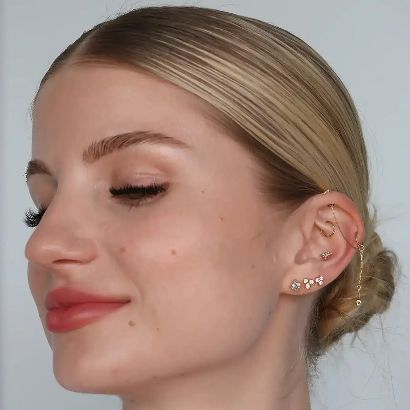 Triple birthstone 14k gold cartilage stud shown on model in helix and lobe piercings, ear stack styling