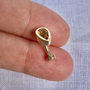 Citrine teardrop floating navel ring in 14k gold held between fingers for size reference