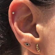 Diamond flat back stud worn in helix cartilage piercing, styled with gold ear jewelry